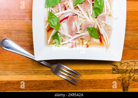 Demi-bol photo sur un repas de Pho Lao maison soupe de nouilles de style avec légumes et feuilles de basilic sur bois barre de coupe avec fourche Banque D'Images