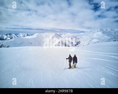 Skieur et snowboardeur debout sur le sommet de la montagne contre le ciel bleu et le panorama des montagnes. Deux amis actifs ont des vacances sur le concept de station de ski. Antenne Banque D'Images