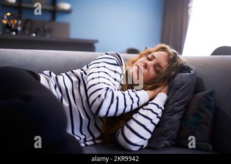 Une fille dort sur un canapé confortable dans la salle de séjour à l'heure de la sieste. Femme dormant prenant la sieste sur le canapé pendant la journée. Banque D'Images