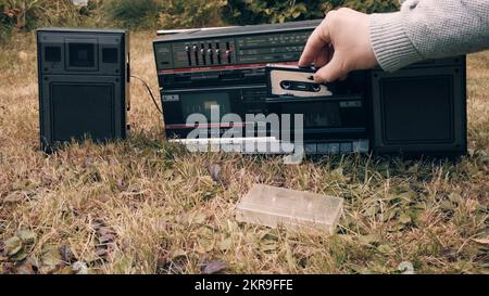 Man sort la cassette de son étui l'insère dans l'ancien enregistreur rétro Banque D'Images