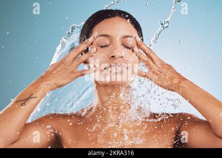 Eau, éclaboussures et femme noire avec douche pour la beauté et le nettoyage du visage, l'hydratation et le toilettage avec fond bleu studio. Éclaboussures d'eau, nettoyer et Banque D'Images