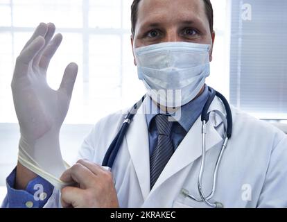 L'enfer prendre soin de vos besoins médicaux. Un médecin masculin mettant un gant en caoutchouc. Banque D'Images