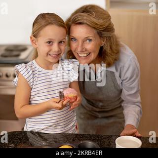 Pas mal pour une première minuterie, Hé. Portrait d'une petite fille et de sa grand-mère debout avec un cupcake dans la cuisine. Banque D'Images