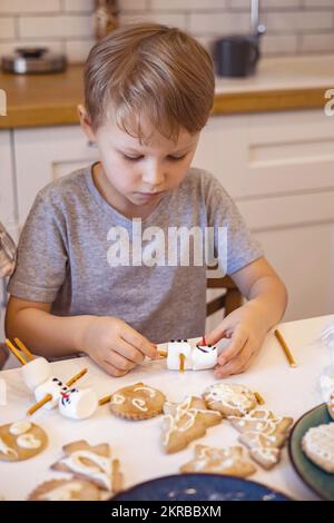 Les parents et les enfants font des bonshommes de neige à partir de guimauves. Ils boivent du cacao et se préparent pour Noël. Concept de la maison de Noël. Banque D'Images