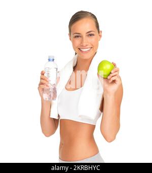 Tout est possible si vous faites de l'exercice et mangez sain. Portrait d'une jeune femme sportive tenant une pomme et une bouteille d'eau contre un blanc Banque D'Images