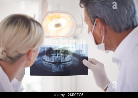 Regarder les rayons X. Vue arrière d'un dentiste et de son assistant regardant une radiographie. Banque D'Images