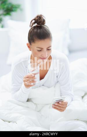 Jeune femme brunet se reposant au lit avec de l'eau Banque D'Images