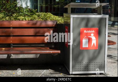 Une poubelle devant les places publiques et un lit de jardin dans une ville australienne. Banque D'Images