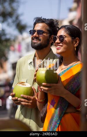 Portrait d'un jeune couple qui boit de l'eau de coco verte dans la rue Banque D'Images