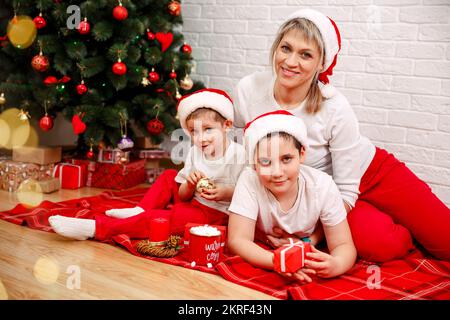 Mère avec des fils assis près de l'arbre de Noël. Vacances. Joyeux Noël Banque D'Images