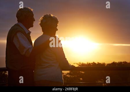 Leur anniversaire d'or. un couple âgé regardant la vue au coucher du soleil. Banque D'Images