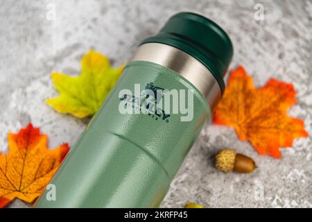 Antalya, Turquie - 28 novembre 2022: Stanley action Trigger thermos mug avec des feuilles dans les couleurs d'automne sur fond de pierre Banque D'Images