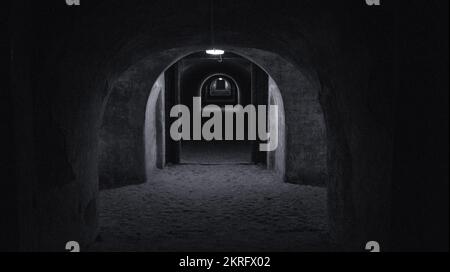 Un long tunnel sombre d'un abri de bombe avec une lumière à l'extrémité du tunnel. Abri d'un abri à la bombe en temps de guerre. Salle souterraine Banque D'Images