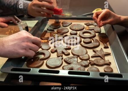 Un groupe d'amis se sont réunis dans la soirée et passent du temps ensemble à cuisiner des biscuits au pain d'épice. Banque D'Images