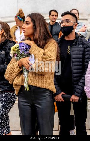 Une jeune femme attend pour déposer un hommage floral aux portes de Buckingham Palace après la mort de la reine Elizabeth II, Londres, Royaume-Uni. Banque D'Images