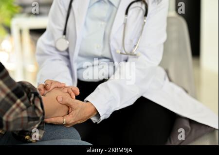 Médecin asiatique professionnel tenant les mains d'un patient, offrant un soutien et rassurant tout en ayant un examen médical. prise de vue rognée Banque D'Images