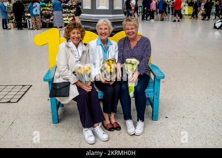 Un groupe de femmes séniors à Victoria Station avec des grappes de fleurs sur leur chemin vers Buckingham Palace après la mort de la Reine, Londres, Royaume-Uni. Banque D'Images