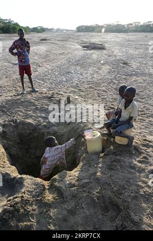 KENYA, Turkana, Lokichar, changement climatique, rivière sèche Lagger, Les Turkana purent de l'eau dans les trous d'eau dans le lit de la rivière / KENIA, Turkana, Klimawandel, trockenes Flußbett Fluß Lagger, Menschen schöpfen wasser aus einem Wasserloch Banque D'Images