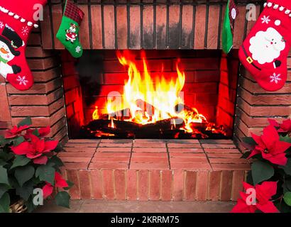 Une fausse cheminée est une décoration de Noël. Chaussettes de Noël, poinsettia. Et le feu qui brûle sur l'écran plasma est comme un vrai feu. Banque D'Images