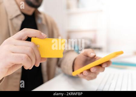 Gros plan de l'homme tenant une carte de crédit et utilisant un smartphone à la maison - achats en ligne Banque D'Images