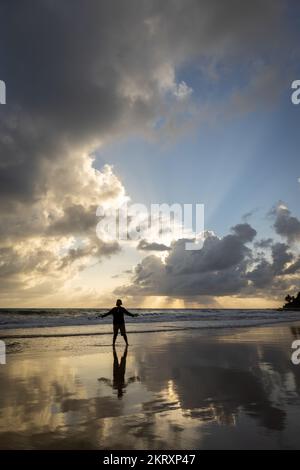 Hipster regardant un homme blanc d'âge moyen sur la plage qui fait du yoga au lever du soleil. Banque D'Images