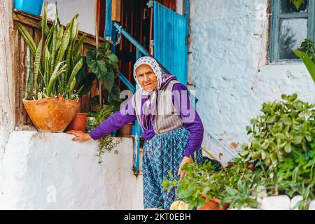 Kash, Turquie - 28 novembre 2022: Vieille femme turque près de sa maison avec des plantes dans la rue touristique de Kas. Photo de haute qualité Banque D'Images