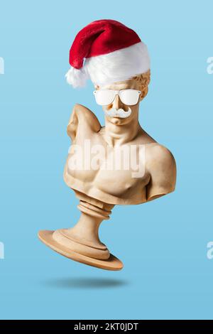 Mise en page créative avec ancienne statue en chapeau de père Noël sur fond bleu clair. Concept de Noël ou de nouvel an minimal. Banque D'Images