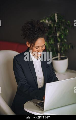 Femme dactylographiant sur un ordinateur portable assis au bureau Banque D'Images