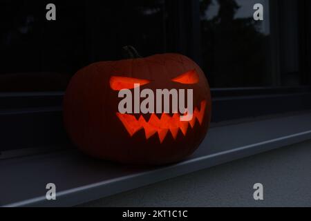 Citrouille d'halloween créative sculptée dans le noir sur un rebord de fenêtre Banque D'Images