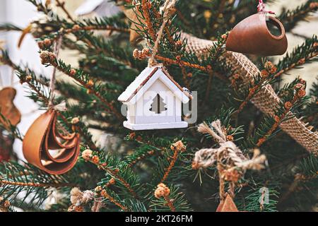 Maison de jouets en bois vintage sur l'arbre de Noël. Décorations de Noël naturelles pour arbre de Noël, zéro déchet Banque D'Images