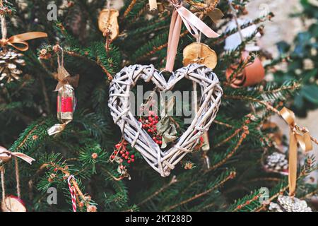 Arbre de Noël décoré d'une couronne en osier en forme de cœur et d'autres ornements de Noël faits main sans déchets Banque D'Images