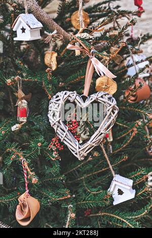 Arbre de Noël décoré d'une couronne en osier en forme de cœur et d'autres ornements de Noël faits main sans déchets Banque D'Images