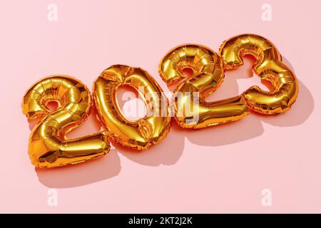 gros plan de quatre ballons en forme de nombre doré formant le numéro 2023, comme la nouvelle année, sur un fond rose Banque D'Images