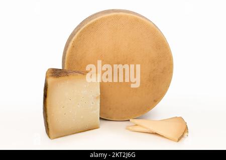 Fromage entier à côté d'un coin et quelques portions texturées sur leurs ringes. Banque D'Images