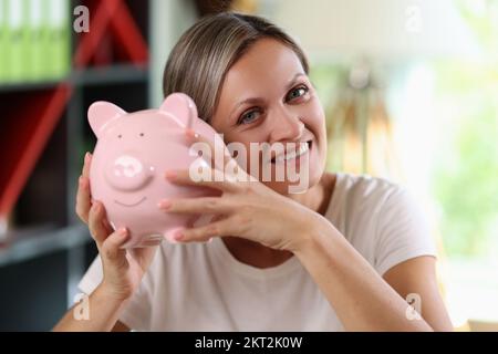 Bonne femme tenant une grande banque de porc dans ses mains et regardant la caméra de près. Banque D'Images