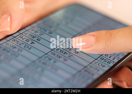 Gros plan de la main de la femme tenant le téléphone mobile avec des données financières à l'écran. Banque D'Images