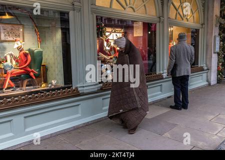 Homelessman devant Fortnum & Mason à Londres aux fenêtres de Noël du Fortnum pendant la période de fête qui a précédé Noël 2022. Banque D'Images