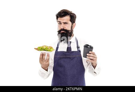 Concept Cafe Food. Homme barbu serveur porter tablier porte plaque avec nourriture et tasse de café. Délicieux croissant. Profitez de votre repas. Un gars qui sert un croissant Banque D'Images