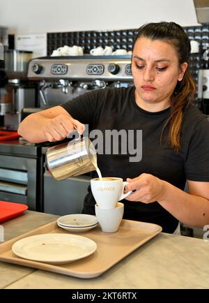 Une femme verse un pot de lait chaud dans un café dans un petit café de boulangerie Banque D'Images