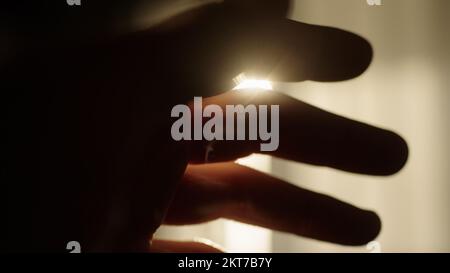 homme à la main jouant avec le reflet de la lumière du soleil à travers la fenêtre, photo large Banque D'Images