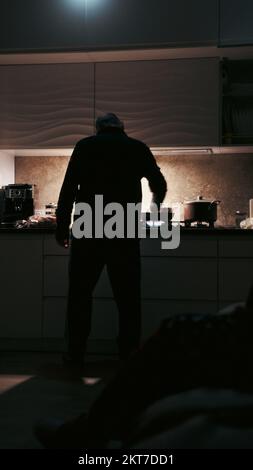 Homme cuisinant avec des lampes torches sur une cuisine pendant la panne de courant en ukraine. Concept d'interdiction en Ukraine. Homme cuisant dans l'obscurité avec des lumières torches autour Banque D'Images