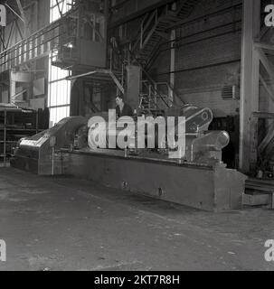1950s, historique, steelworkers, une opérative d'une machine de découpe, de fabrication de tôles d'acier, à l'Abbey Works, Port Talbot, au sud du pays de Galles, Royaume-Uni, qui abrite la Steel Company of Wales Ltd, à cette époque le plus grand site de fabrication d'acier en Europe. Le travailleur utilise une machine fabriquée par la Farrel Co. Une entreprise fondée en 1848 à Ansonia, Connecticut, USA, par Almon Farrel, qui a fabriqué des machines pour le travail du bois. Banque D'Images