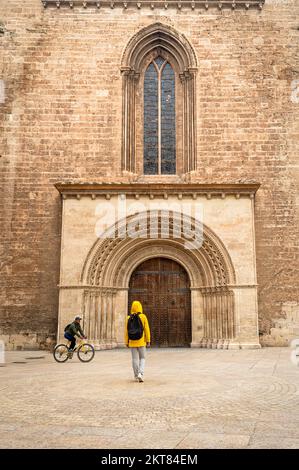 Touriste en manteau jaune à l'entrée de la cathédrale Sainte-Marie, Valence, Espagne. Banque D'Images