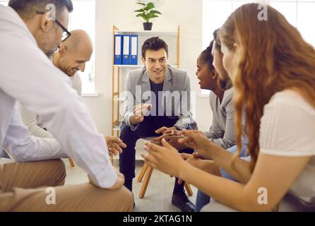 Équipe d'affaires à l'écoute d'un jeune homme qui donne des conseils lors d'une réunion de travail au bureau Banque D'Images