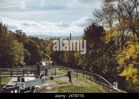 2 personnes près des portes d'écluse (porte d'ouverture) bateaux amarrés et ensoleillées Damart Mill - Bingley Five Rise Locks, Leeds & Liverpool Canal, West Yorkshire Angleterre Royaume-Uni. Banque D'Images