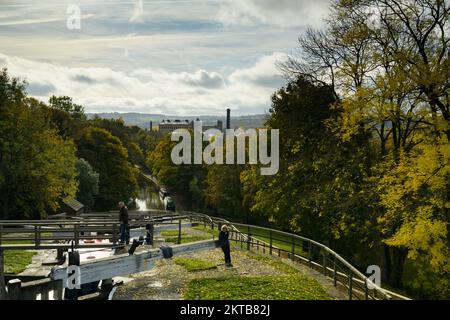 2 personnes près des portes d'écluse (porte d'ouverture) bateaux amarrés et ensoleillées Damart Mill - Bingley Five Rise Locks, Leeds & Liverpool Canal, West Yorkshire Angleterre Royaume-Uni. Banque D'Images