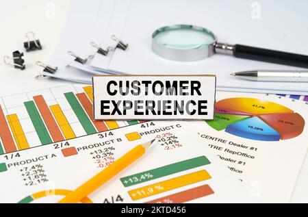 Concept d'entreprise. Sur les graphiques commerciaux se trouve une loupe, un stylo et un signe avec l'inscription - expérience client Banque D'Images
