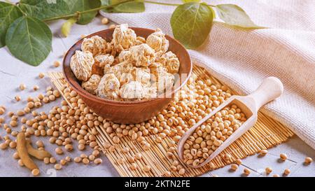 Fragments de protéines de soja texturés (nutri nuggets), viande de soja brute pour les végétaliens dans un bol en argile sur une serviette de bambou sur le fond de la toile de fond et de la branche jeune Banque D'Images