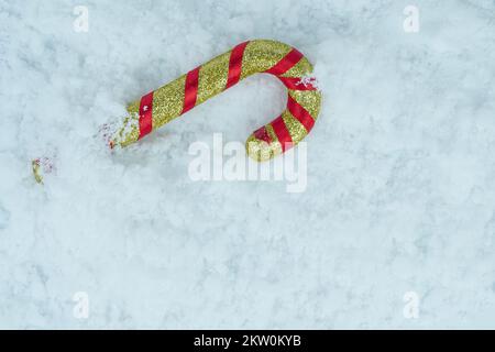 Cannes de bonbon pailletées rouge doré sur la neige blanche. Banque D'Images