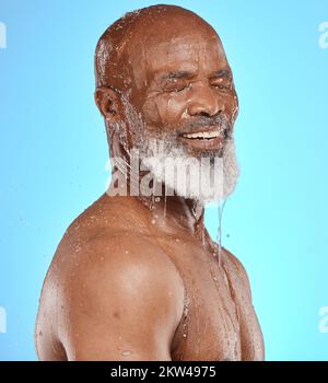 Éclaboussures d'eau, soin de la peau et visage d'homme noir senior en studio isolé sur fond bleu. Nettoyage, hygiène et retraités de sexe masculin du Nigeria Banque D'Images